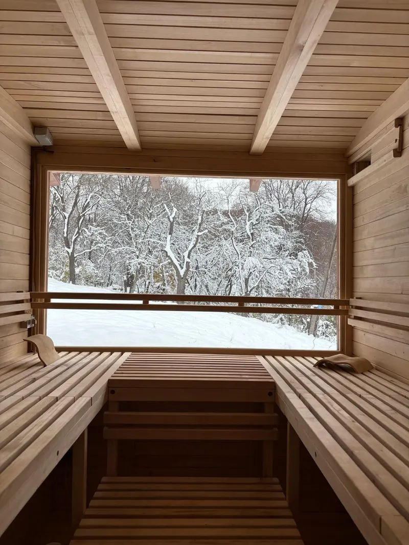 Drevená sauna s oknom do zasnežených stromov