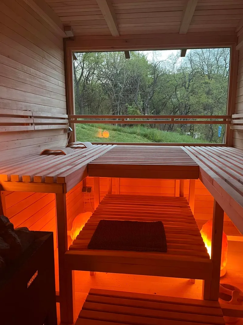 Drevená sauna so žeravým svetlom a oknom do prírody